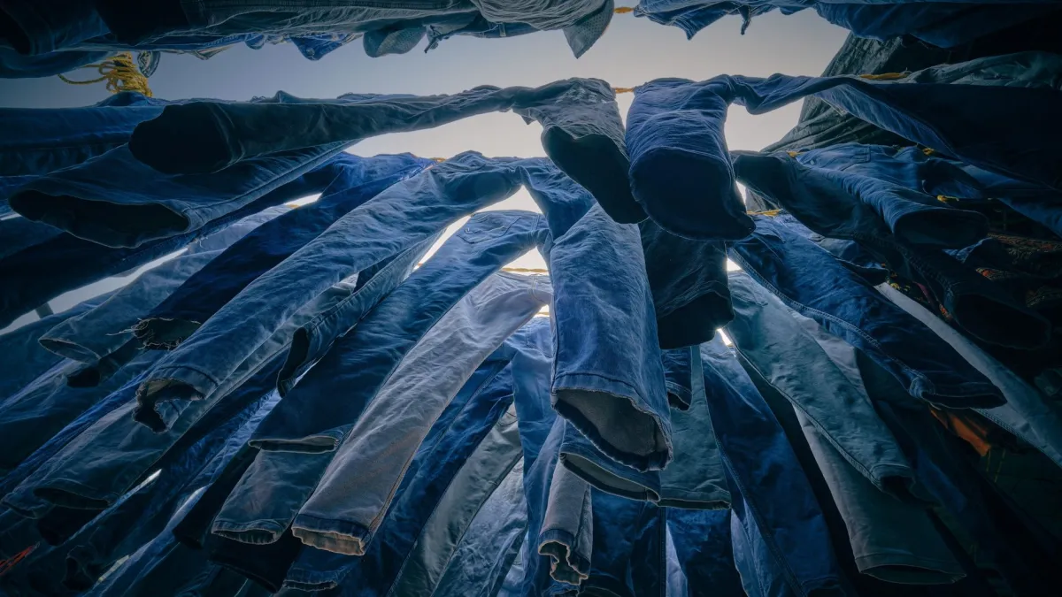 Calças jeans azuis secando em um varal à sombra