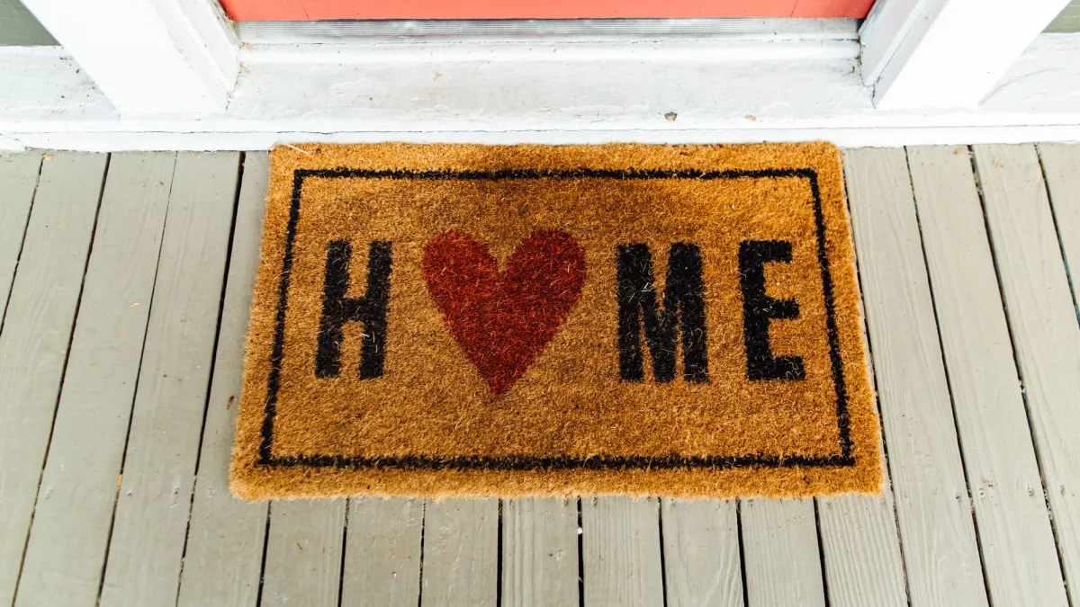 Capacho limpo e de cor neutra posicionado na entrada de uma casa.