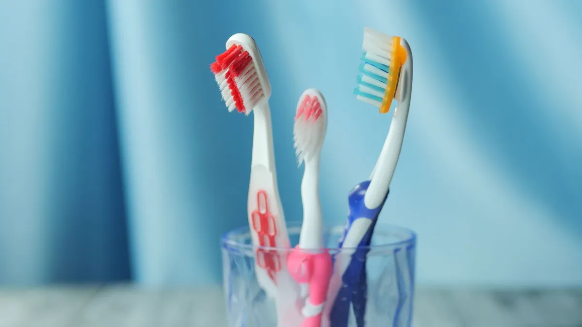 Close-up de uma escova de dentes elétrica sendo limpa com um pano macio, com foco na remoção de resíduos externos.