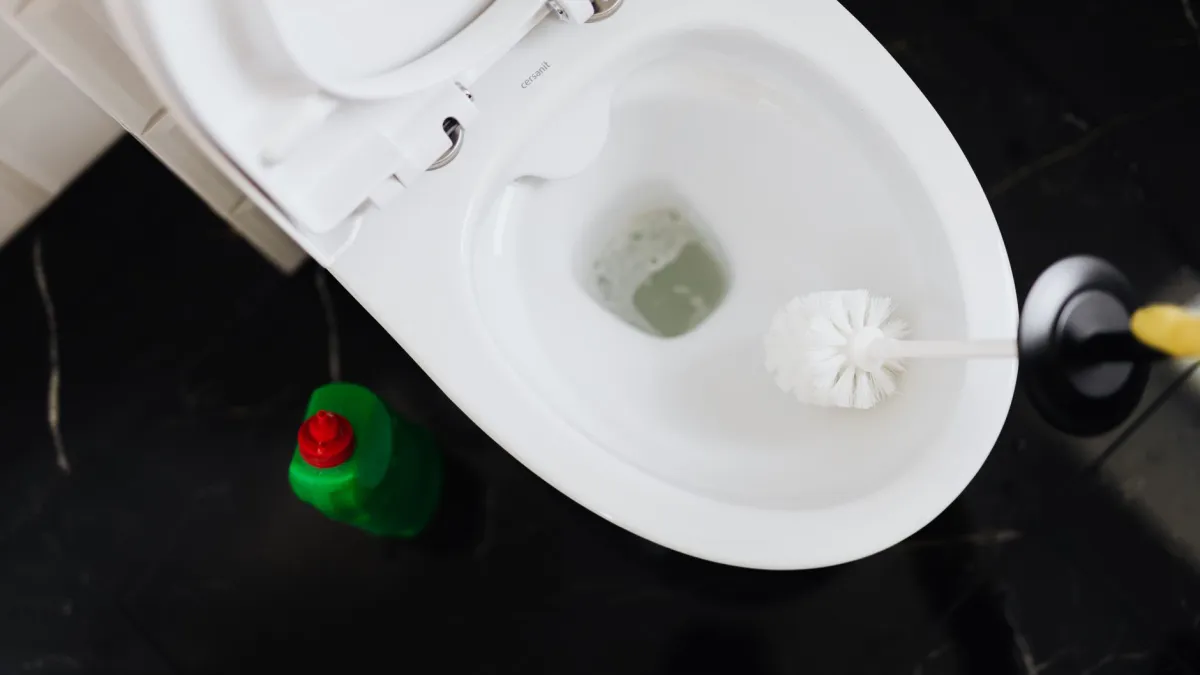 Escova de vaso sanitário com cerdas firmes limpando a borda interna.