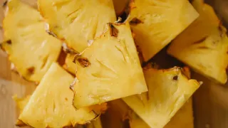 Frutas tropicais frescas cortadas em um recipiente transparente sobre uma mesa de madeira