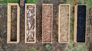Jardineiro adicionando composto a um canteiro elevado de horta.