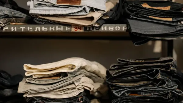 Mulher dobrando calças jeans azuis organizadamente em uma prateleira