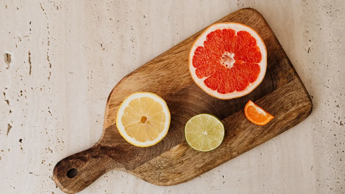 Mulher fatiando uma variedade de frutas coloridas em uma tábua de corte