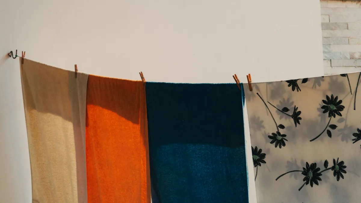 Peças de roupa coloridas secando à sombra em um varal, protegidas do sol direto.