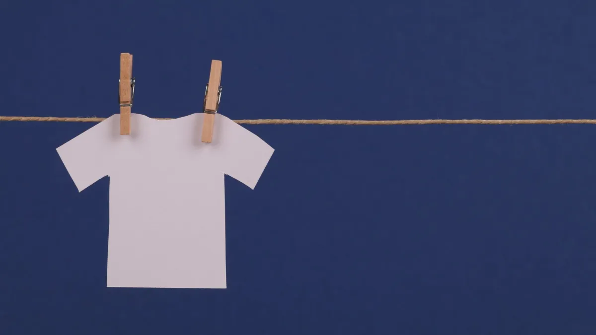 Pregadores de madeira seguros em uma camisa branca pendurada em um varal.
