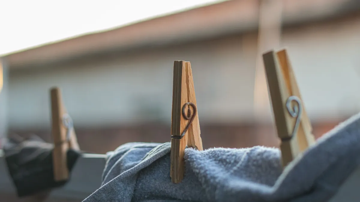 Pregadores de roupa prendendo delicadamente a barra de uma calça jeans em um varal.