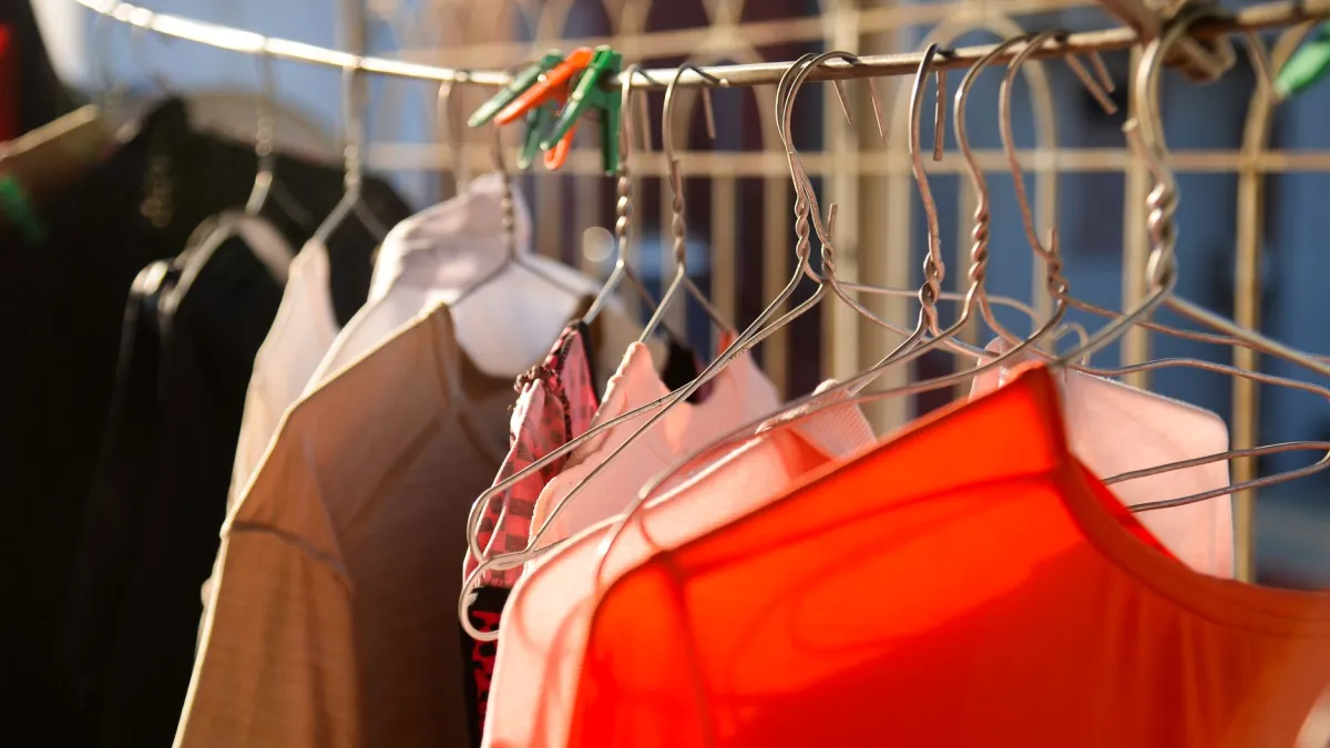 Roupas coloridas vibrantes penduradas em um varal sob a luz do sol, simbolizando a manutenção das cores.