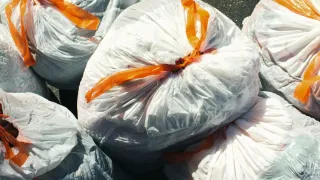 Sacos de lixo cheios e amarrados em uma lixeira de cozinha.