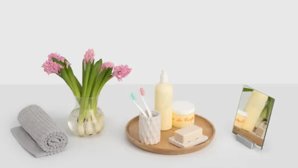 Um banheiro moderno e limpo com um pequeno vaso de planta sobre a bancada e luz natural entrando.