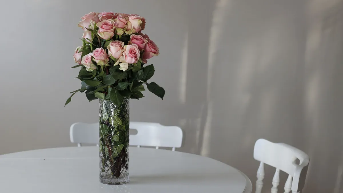 Vaso de cristal com flores de corte coloridas e duradouras sobre uma mesa branca